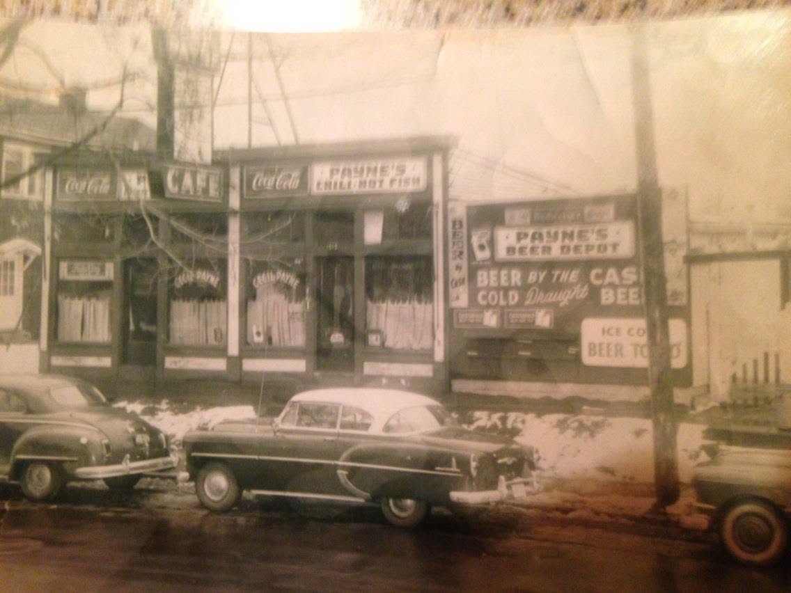 Storefront of Cecil Payne's Cafe on South 32nd Street in Louisville — a mid-century tavern with painted signs reading CAFE, PAYNE'S CHILI HOT FISH, PAYNE'S BEER DEPOT, BEER BY THE COLD DRAUGHT, ICE COLD BEER TO GO, with 1950s cars parked at the snowy curb
